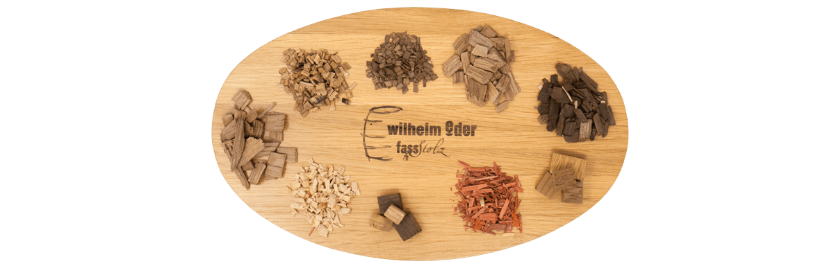 Holzalternativen Auf dem Bild ist eine Holzscheibe mit dem Wilhelm Eder Logo zu sehen und kleine Häufchen an verschiedenen Holzalternativen wie Cubes, Chips und Powder.